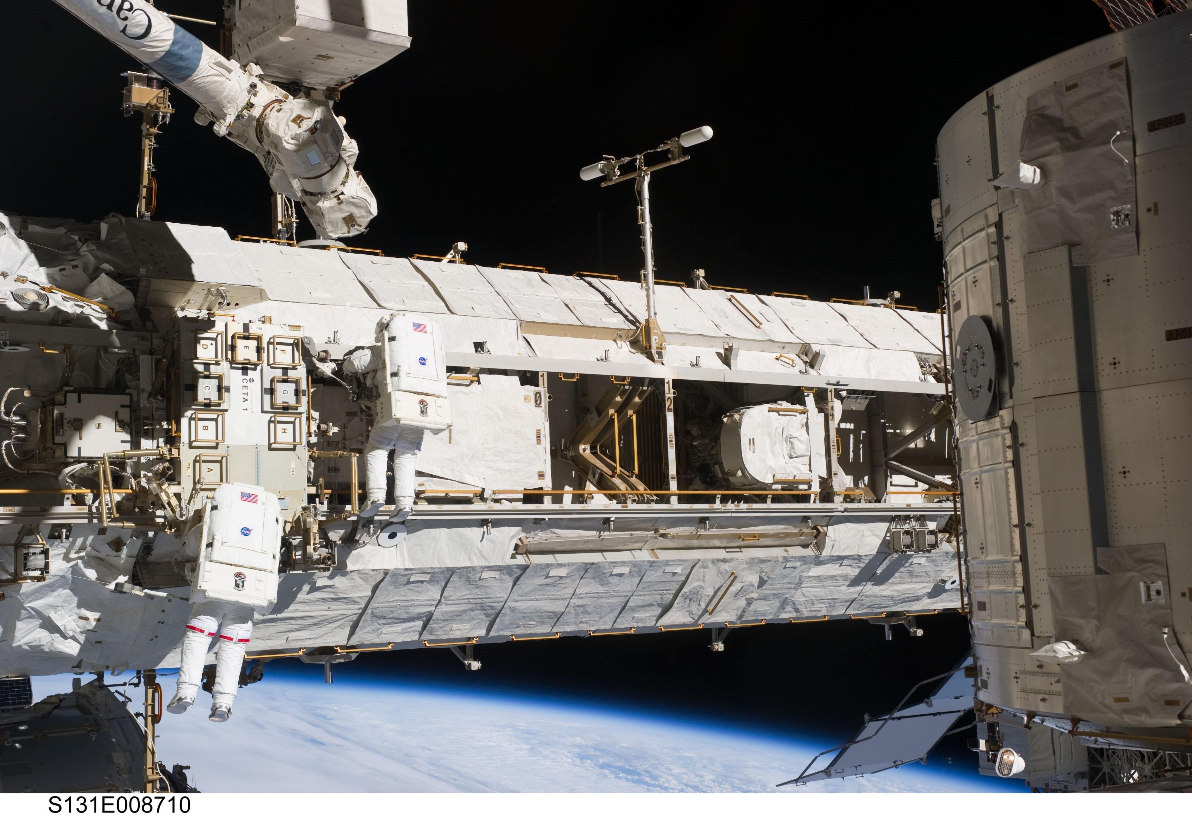 Background image showing astronauts working on maintaining the International Space Station in space.