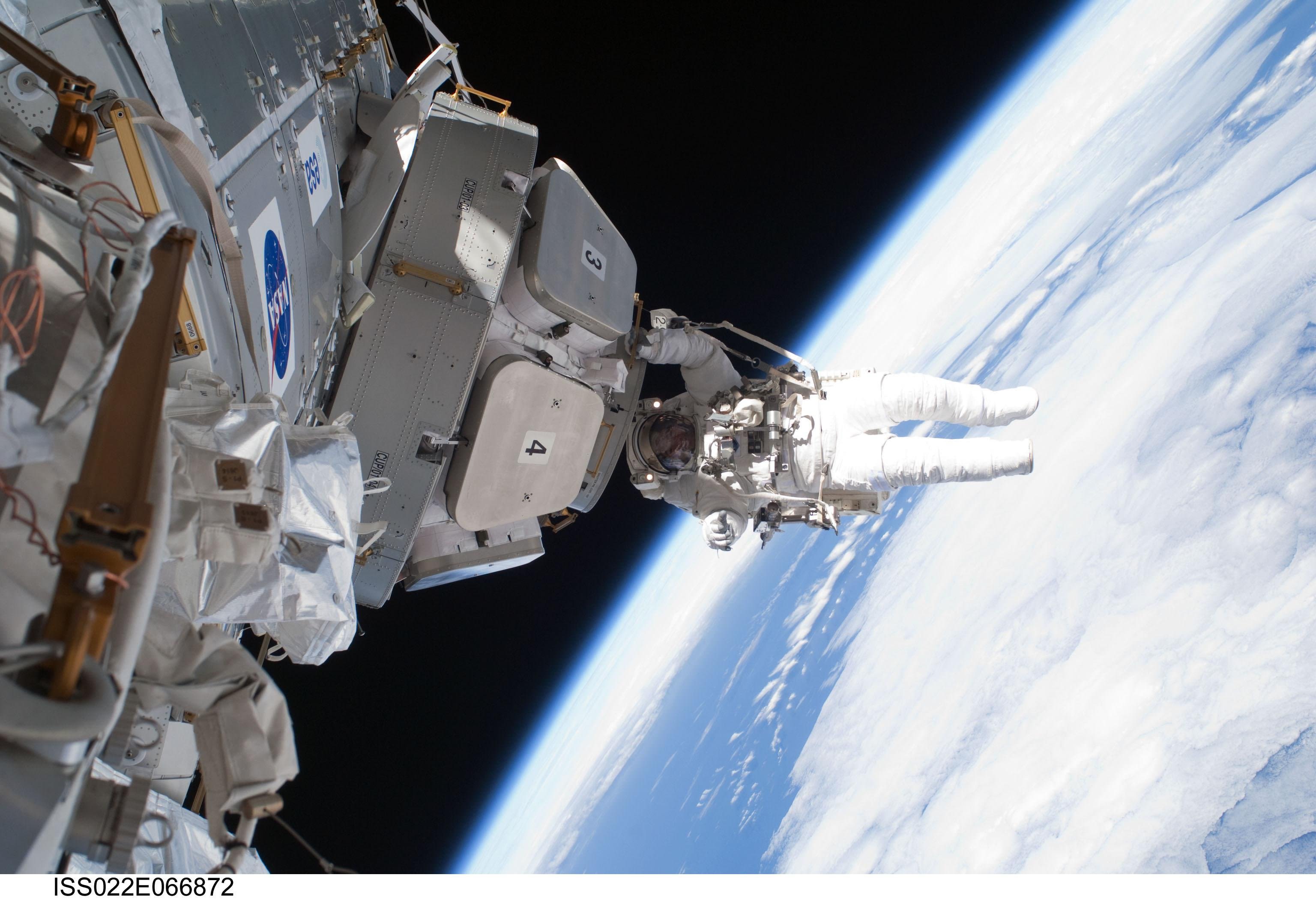 Background image shows an astronaut working on the outside of a spacecraft in space with the Earth in the background.