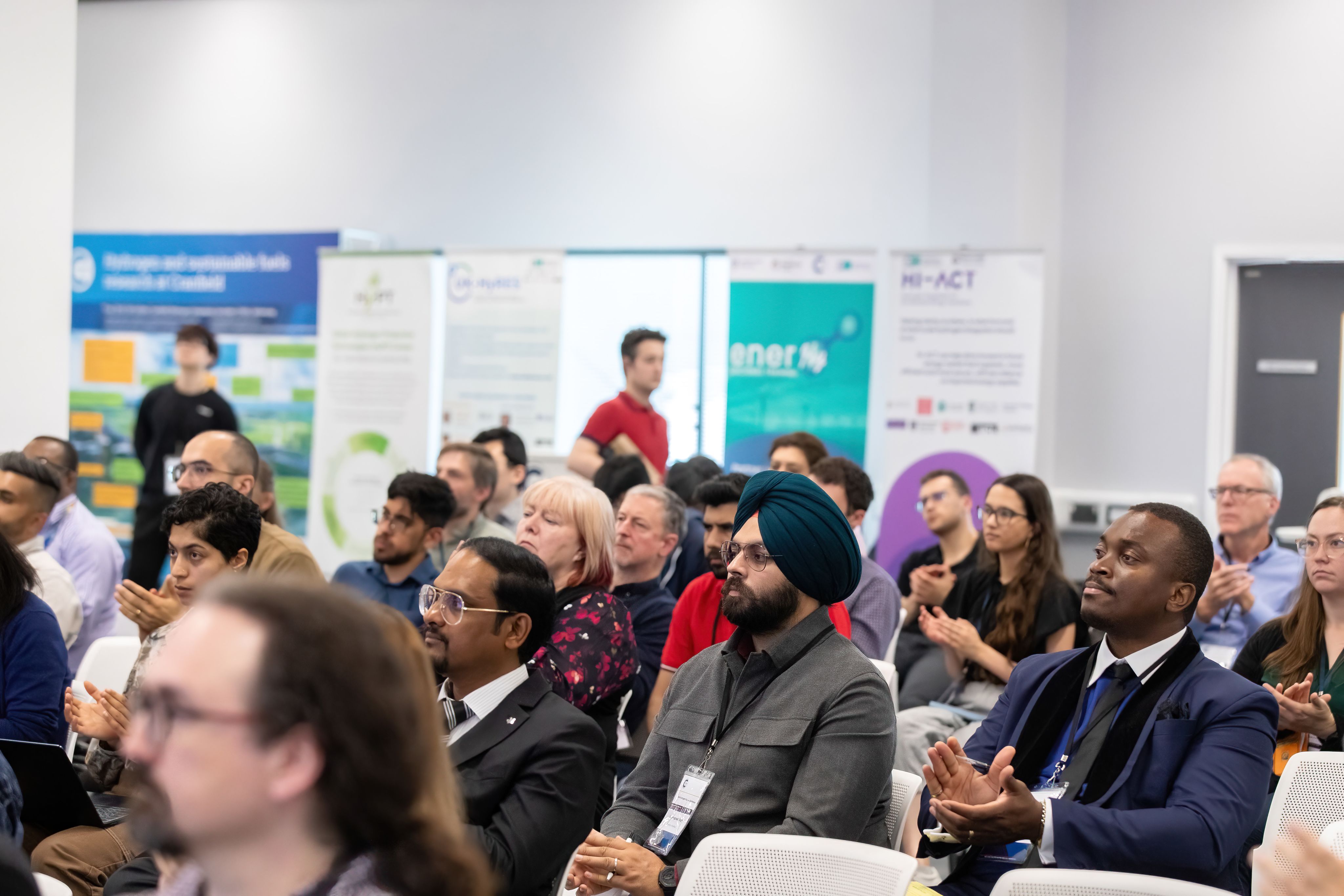 Diverse crowd of scientists and engineers applauding hydrogen presentation